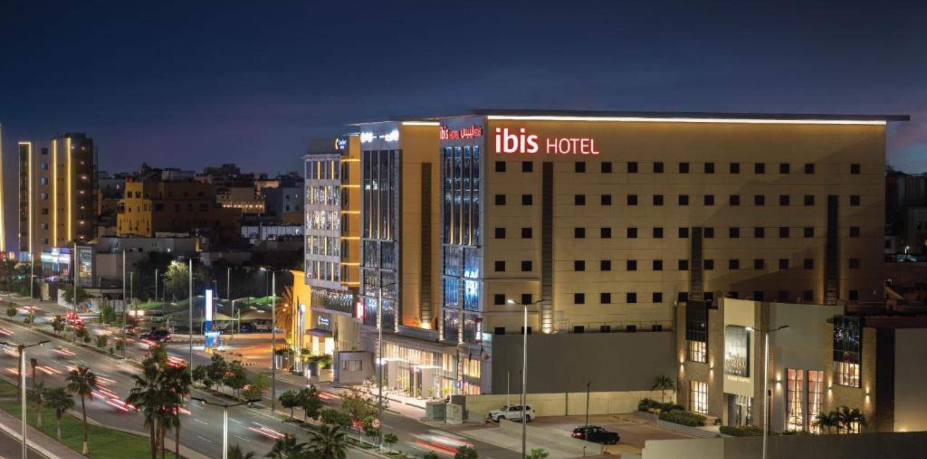 Un hotel moderno con un cartello ben visibile 'ibis HOTEL', caratterizzato da una facciata piatta e numerose finestre.