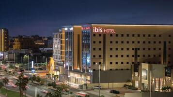 Un hotel moderno con un cartello ben visibile 'ibis HOTEL', caratterizzato da una facciata piatta e numerose finestre.