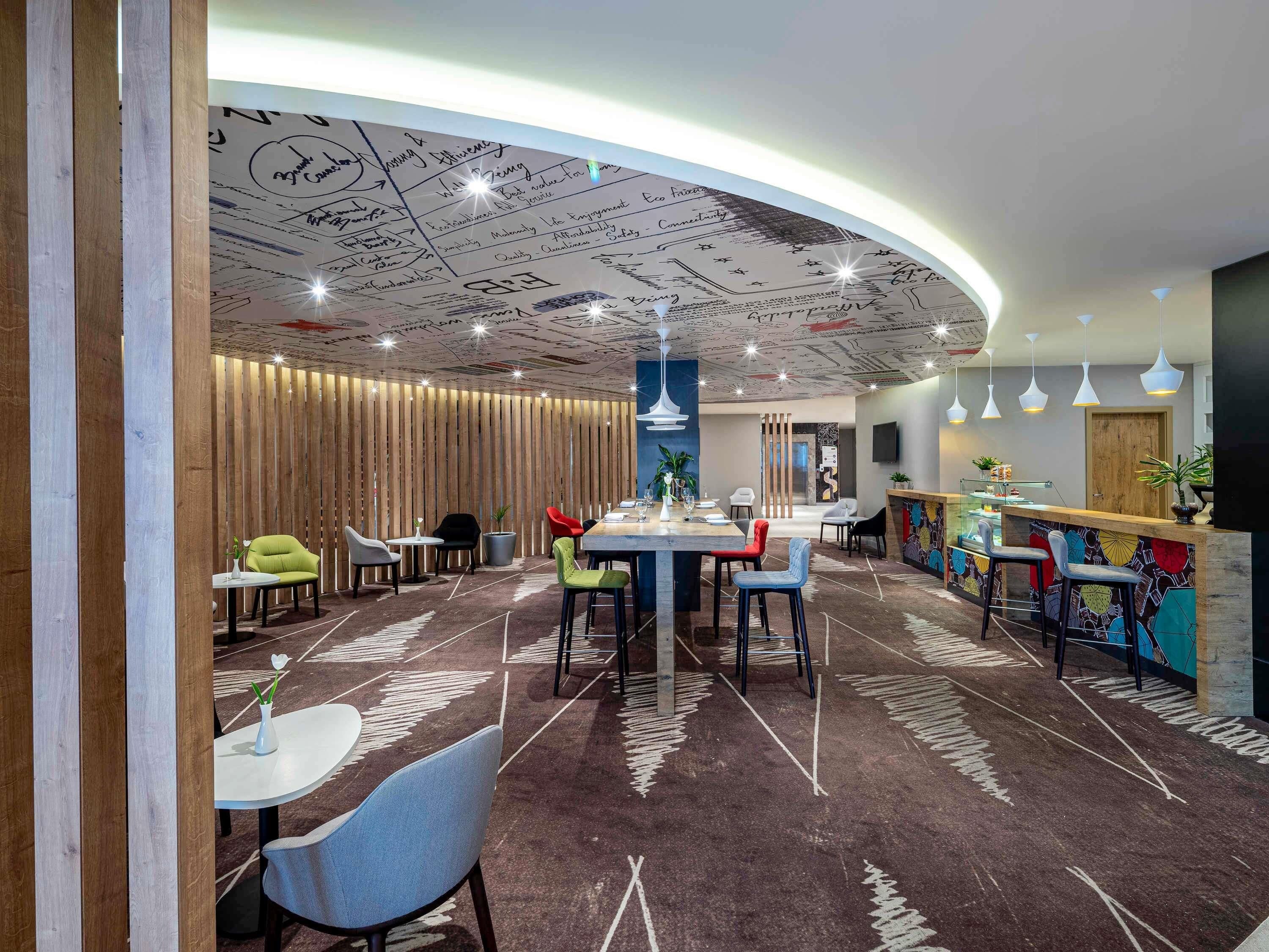 Un ristorante moderno con un'area pranzo centrale, un bar e un soffitto decorato.