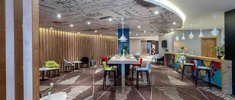 Un ristorante moderno con un'area pranzo centrale, un bar e un soffitto decorato.