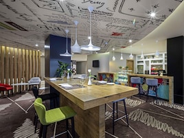 Un espace bar moderne avec un comptoir en bois, des tabourets de bar et un plafond décoratif orné de notes manuscrites.