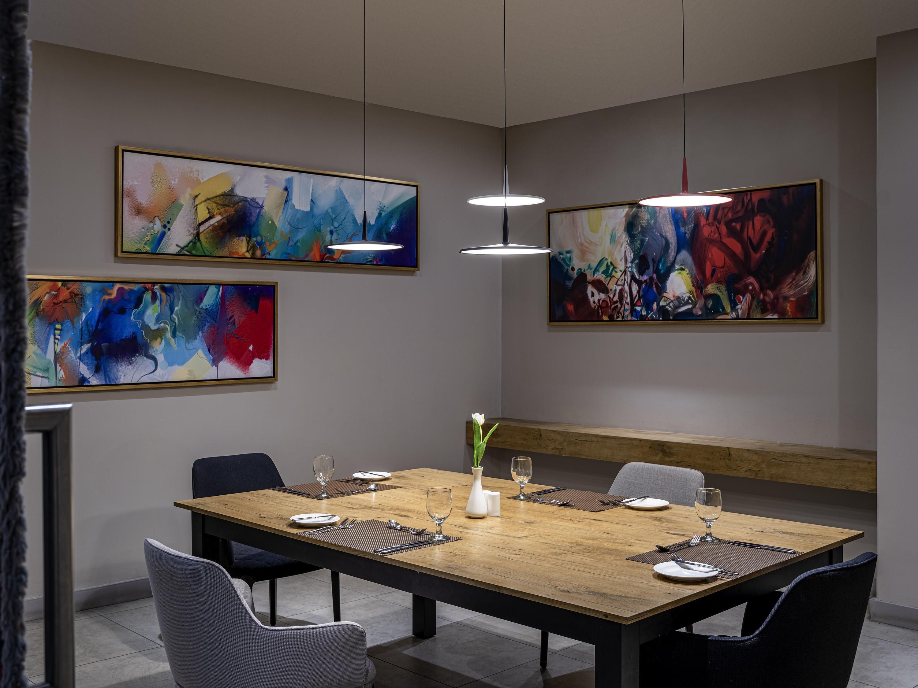 Uma área de jantar moderna com uma mesa de madeira posta para quatro pessoas, rodeada por cadeiras.