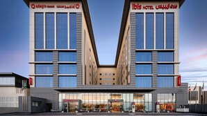 Ein modernes Hotel mit zwei symmetrischen Flügeln, großen Fenstern und einem zentralen Atrium.