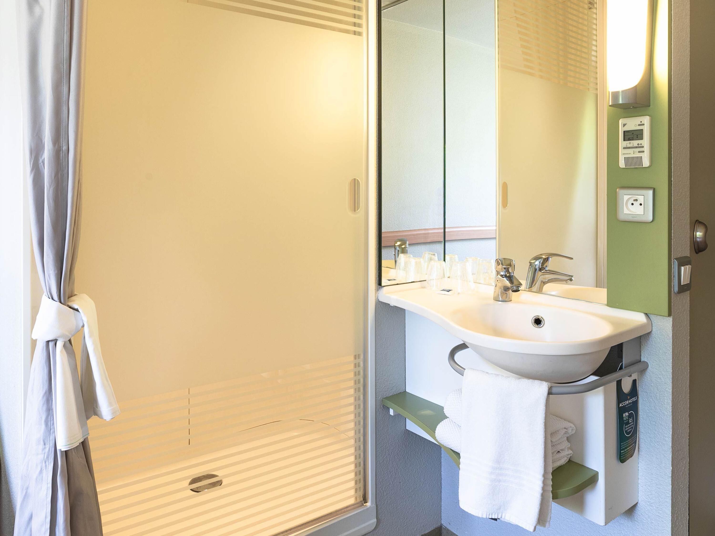 A bathroom with a shower, sink, and mirror.