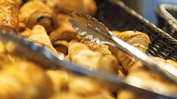 A close-up of pastries with tongs, indicating a bakery or food service setting.