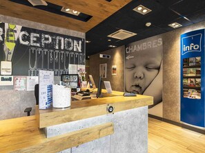 A reception area with a wooden counter, a chalkboard with text, a wall with a large poster, and an 'info' section with brochures.