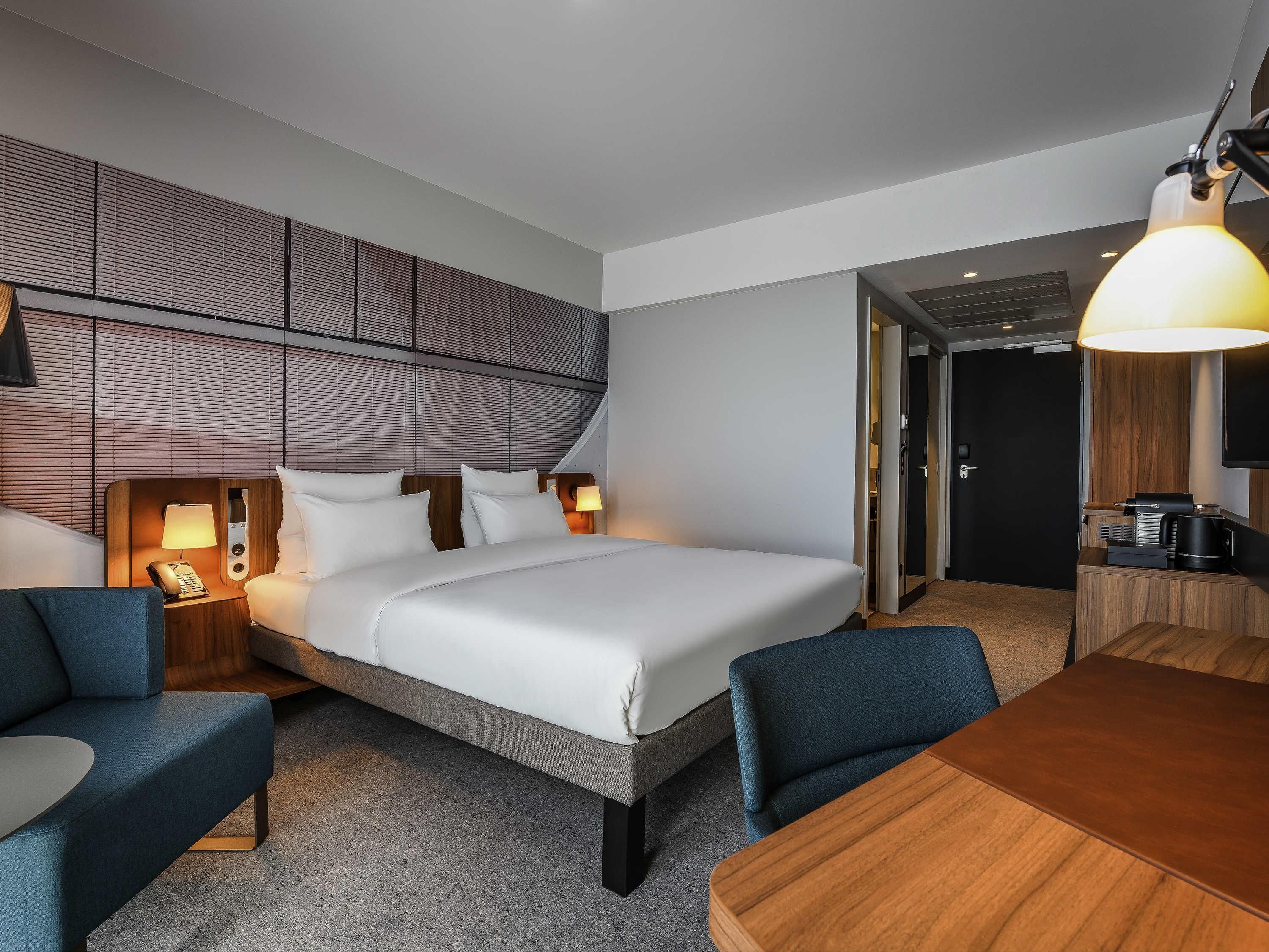 Ein Hotelzimmer mit einem Bett, Nachttischen, einem Schreibtisch und einem Sessel.