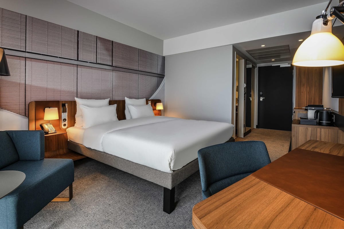 Una habitación de hotel con cama, mesitas de noche, un escritorio y una silla.