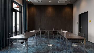 A conference room with a long table, chairs, and a dark wooden wall.