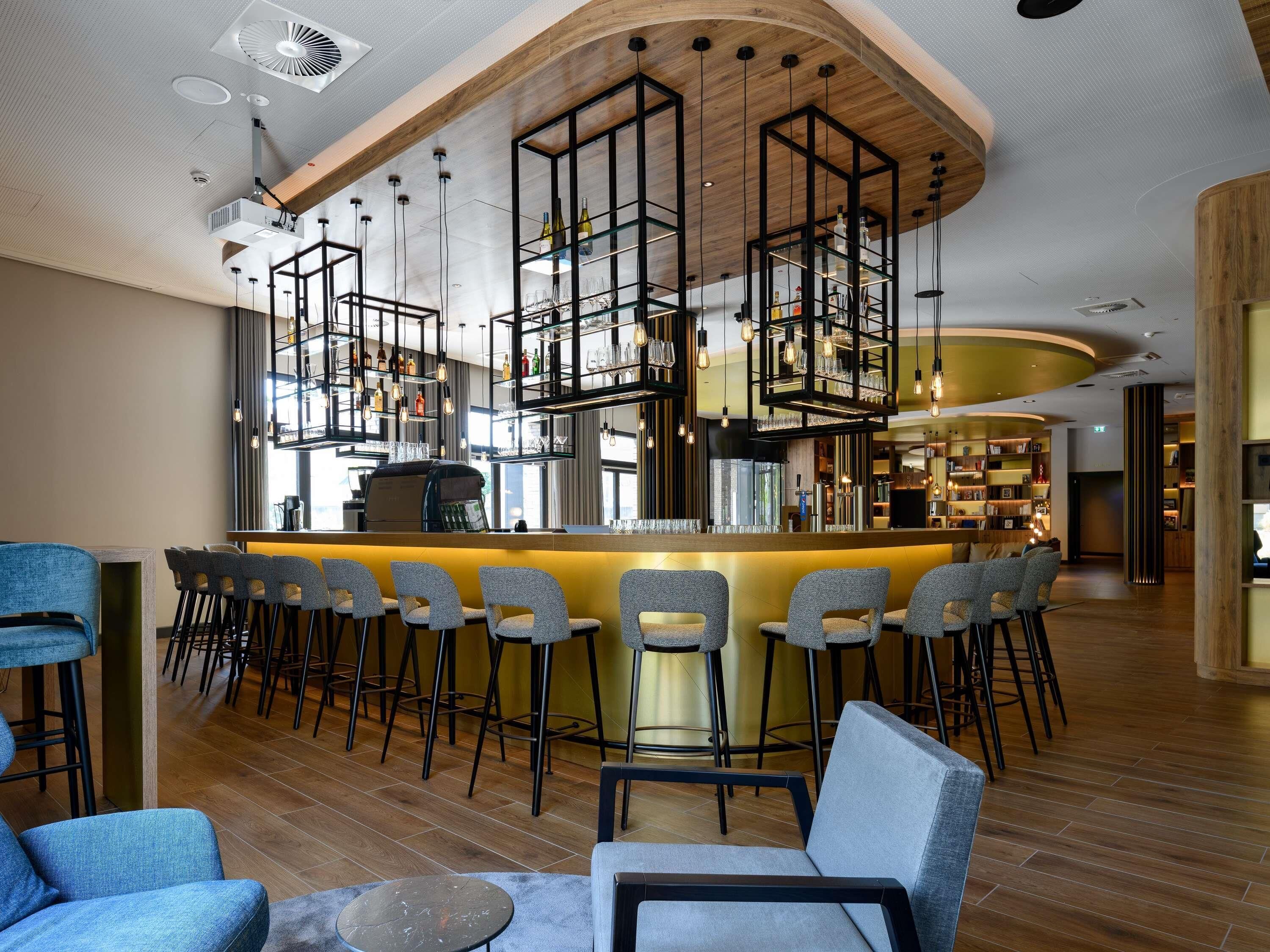 Zona de bar moderna con barra central, diversas opciones de asientos y techo de madera.