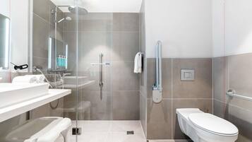 A modern bathroom with a glass shower enclosure, a toilet, and a sink with a bench.