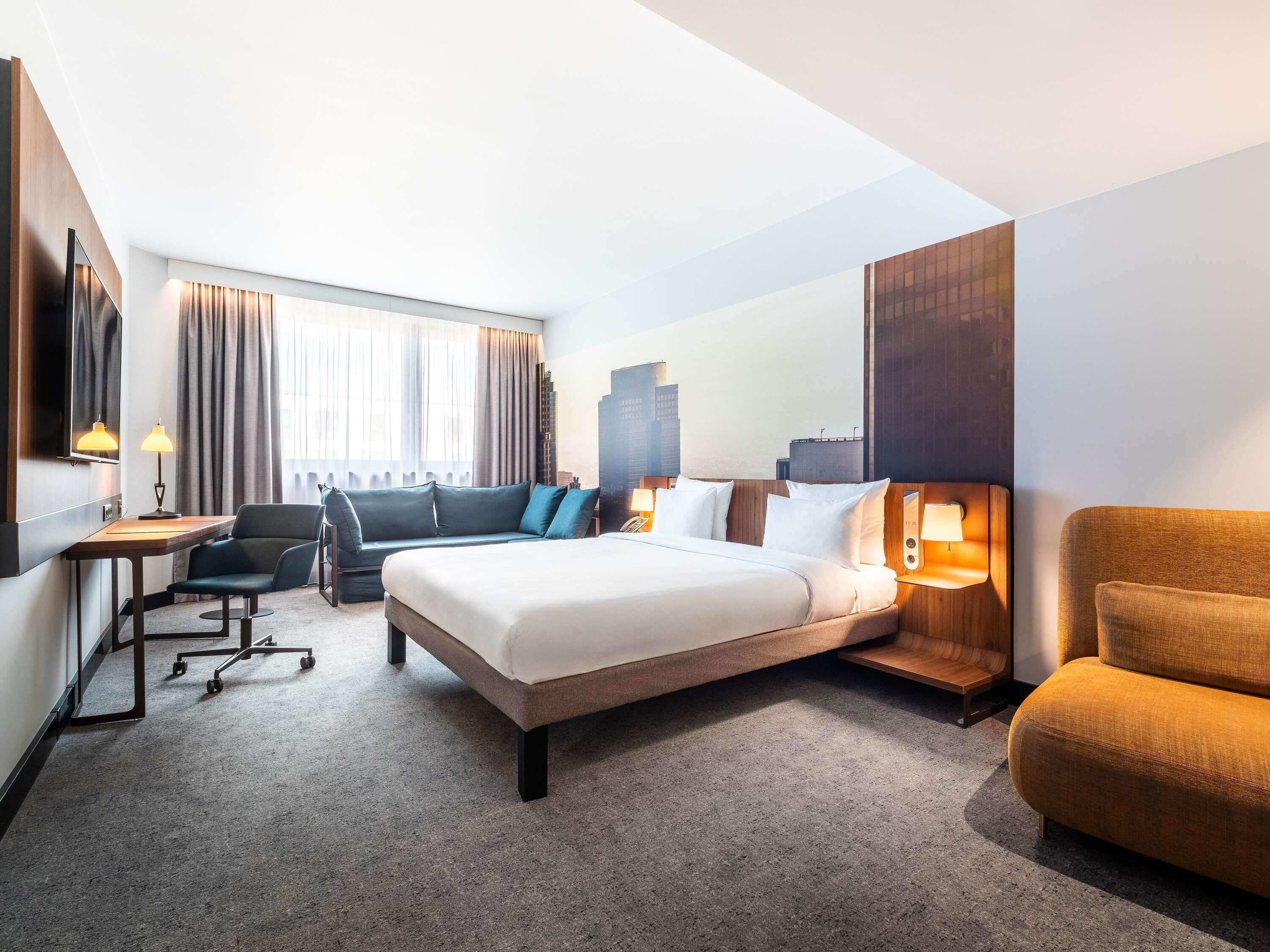 Et hotelværelse med en stor seng, et skrivebord, en stol og en sofa.