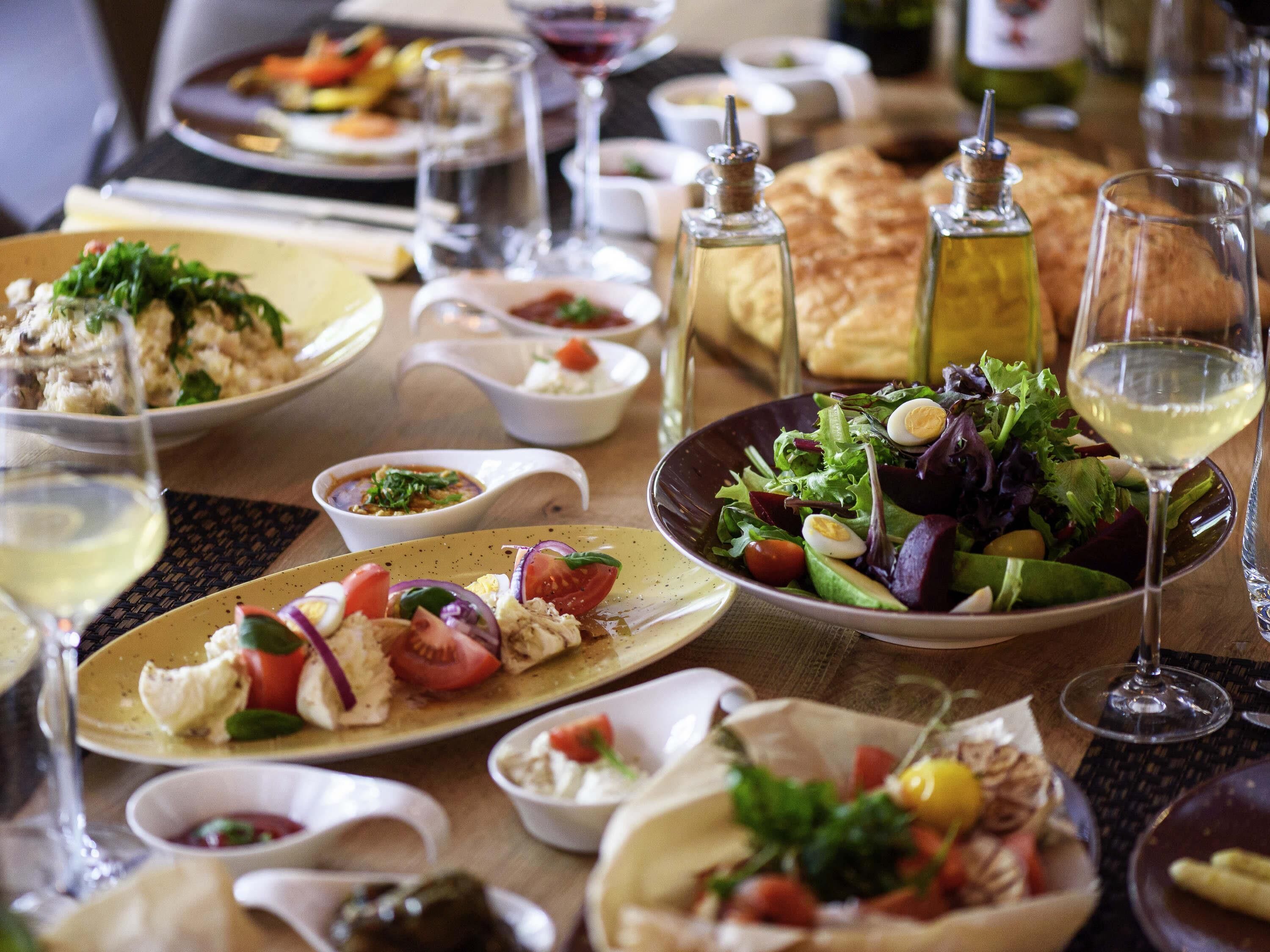 A dining table with various dishes, including salads, bread, and a bowl of soup.