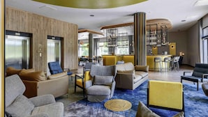 Un moderno vestíbulo de hotel con zonas de estar, un bar y una escalera.