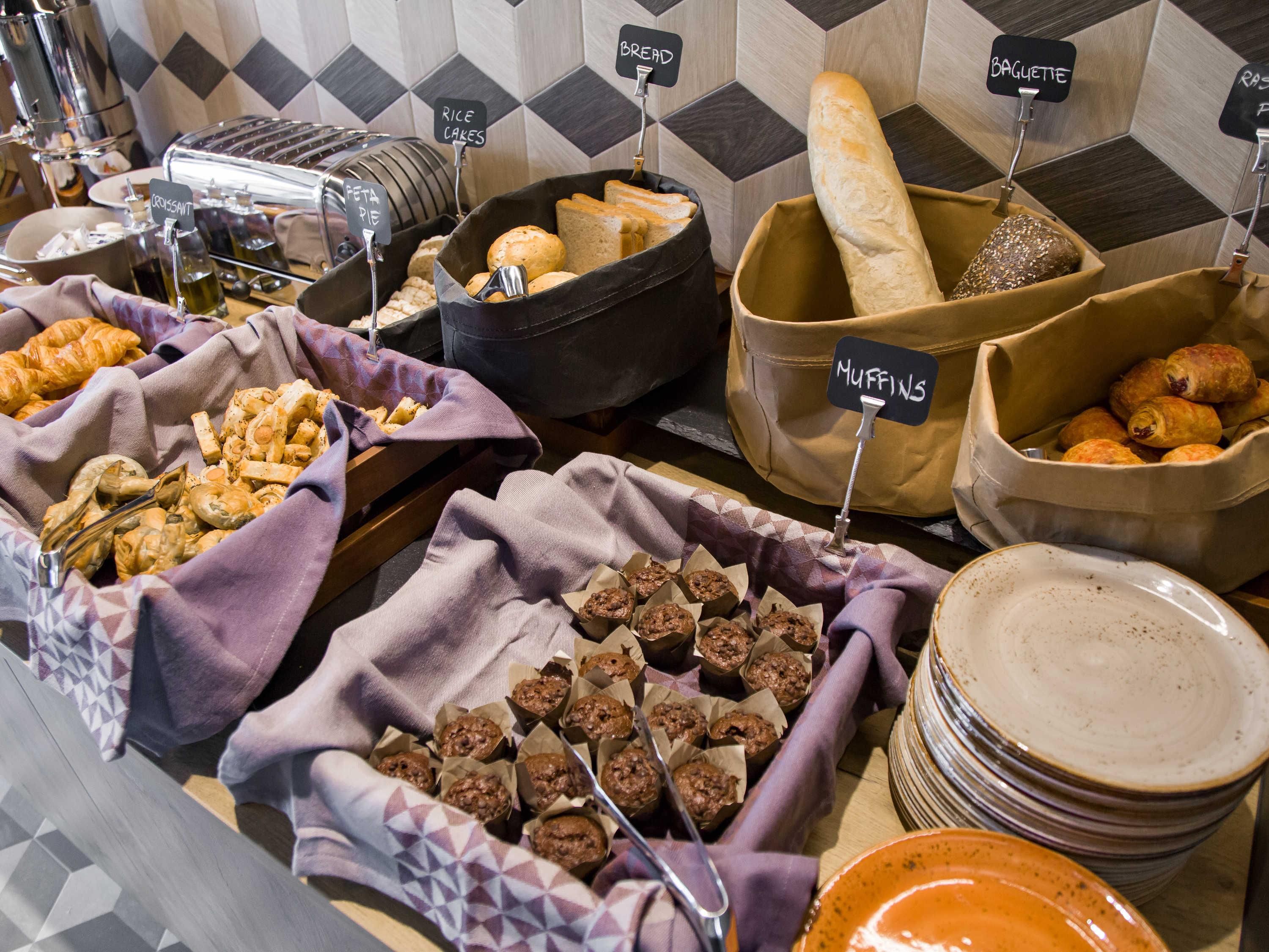 Een buffet met containers met labels voor brood, muffins en rijstwafels.