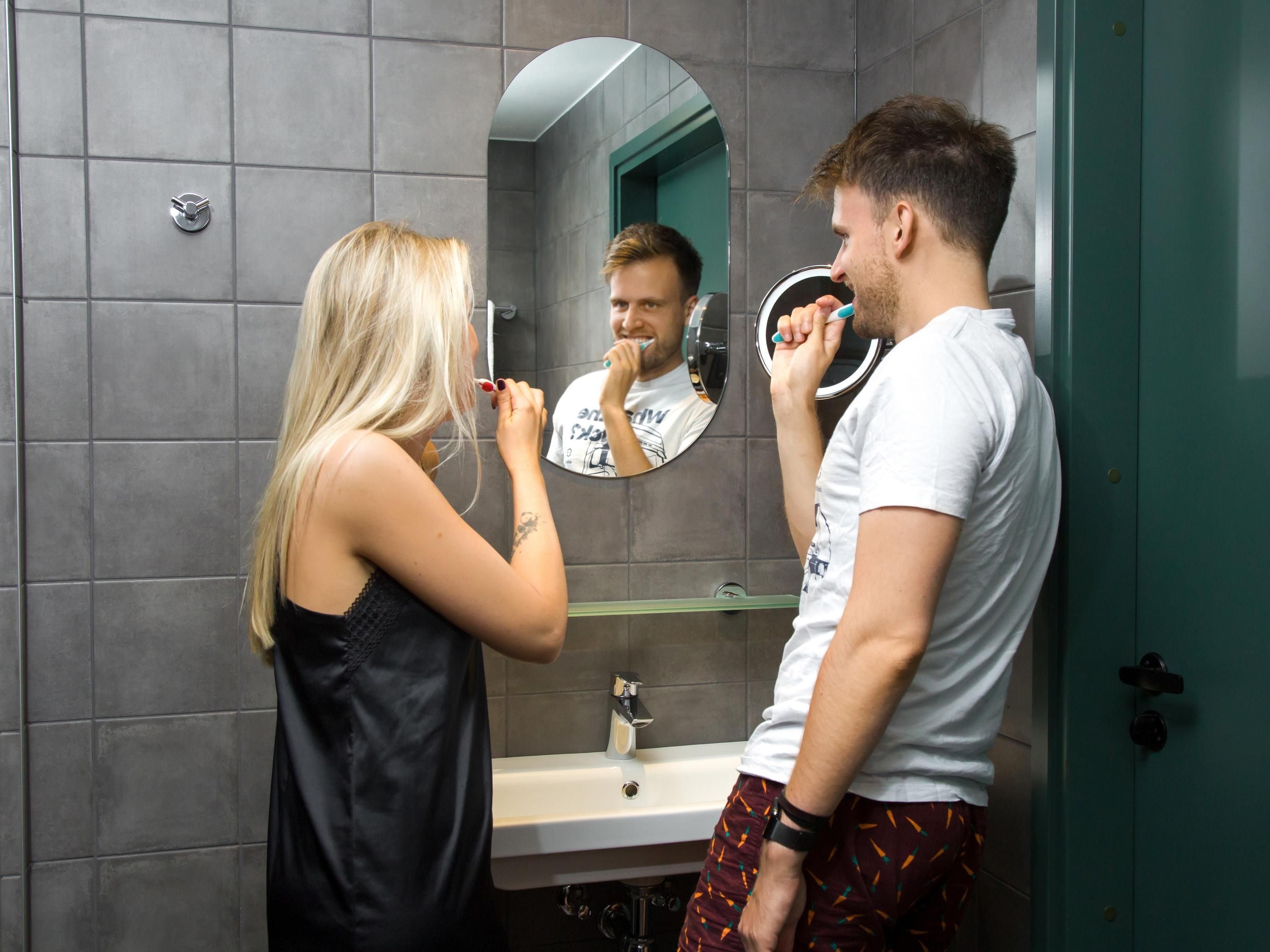 A bathroom with a mirror, sink, and a green door.