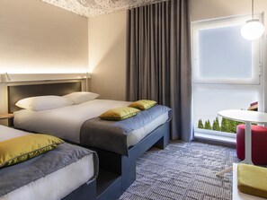 Une chambre d’hôtel avec un lit, une table de chevet, une petite table ronde et une vue sur l’extérieur.