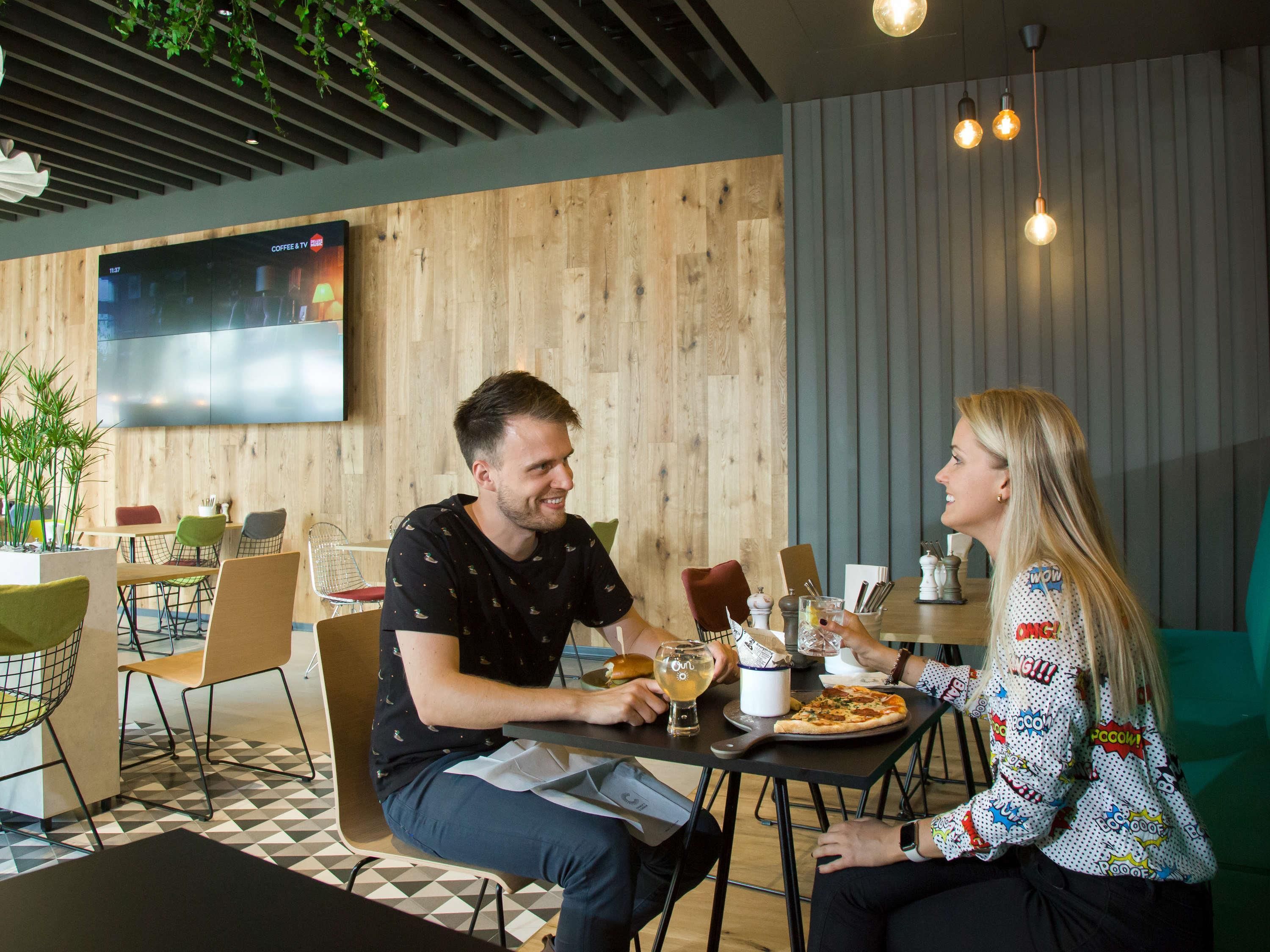 A modern dining area with wooden walls, a flat-screen TV, and a pizza on the table.