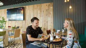 Un comedor moderno con paredes de madera, un televisor de pantalla plana y una pizza sobre la mesa.
