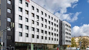 Ein modernes Hotelgebäude mit einem Raster aus Fenstern und einem gut sichtbaren 'ibis hotel' Schild.