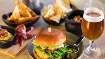 A burger with a side of chips and a glass of beer on a wooden table.