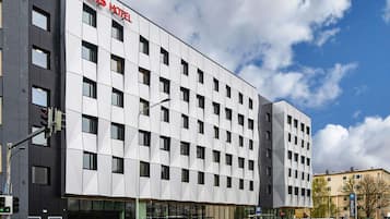 Um hotel moderno com fachada em grade de janelas e um letreiro grande com a inscrição 'ibis hotel'.