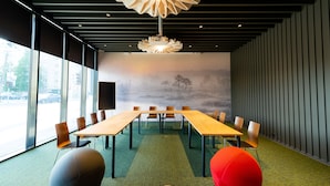 Une salle de conférence équipée d’une longue table, de chaises et d’un grand écran.