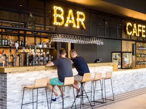 Un bar et un café au design moderne, avec un comptoir doté de plusieurs robinets et un présentoir à bouteilles de vin.