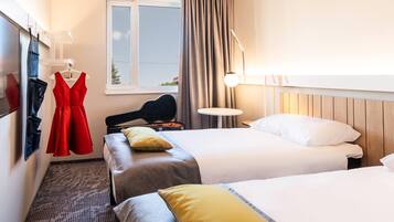Habitación de hotel con dos camas, un vestido rojo colgado en la pared, una guitarra y una ventana con cortinas.