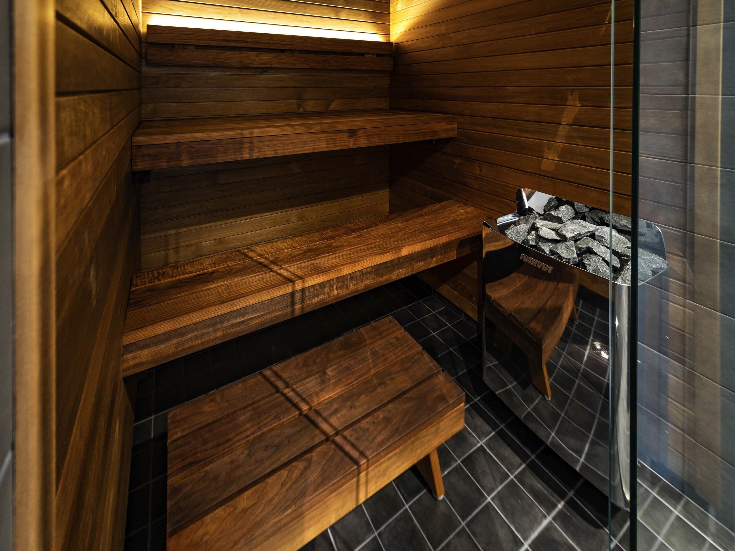 Una sauna amb bancs de fusta i una porta de vidre.