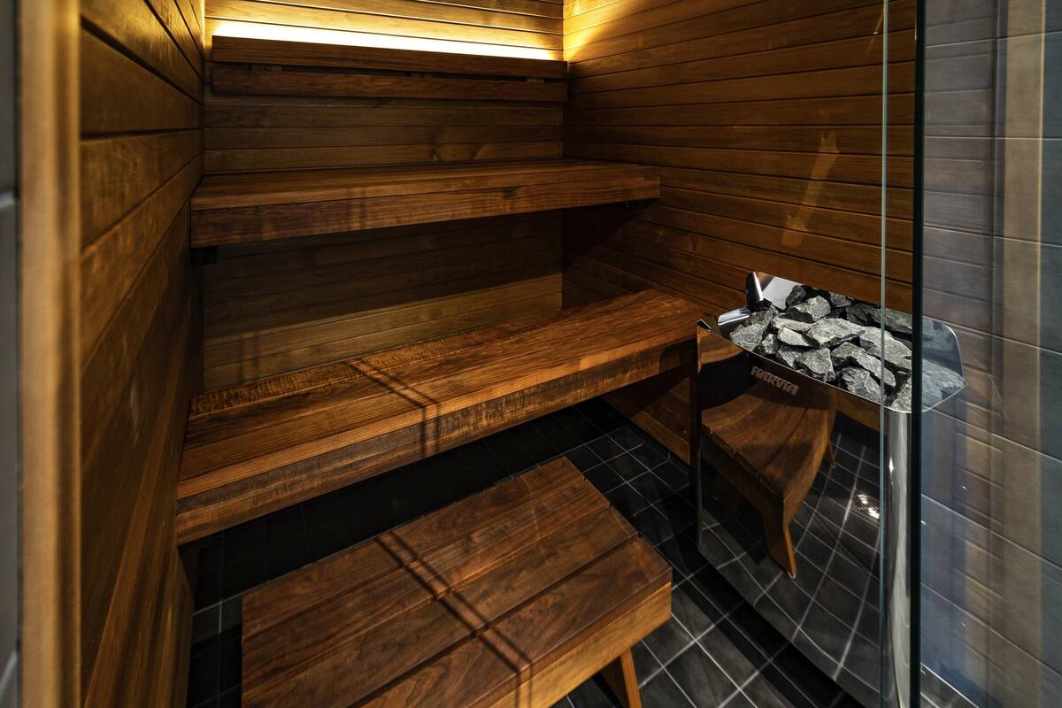 Un sauna avec des bancs en bois et une porte en verre.