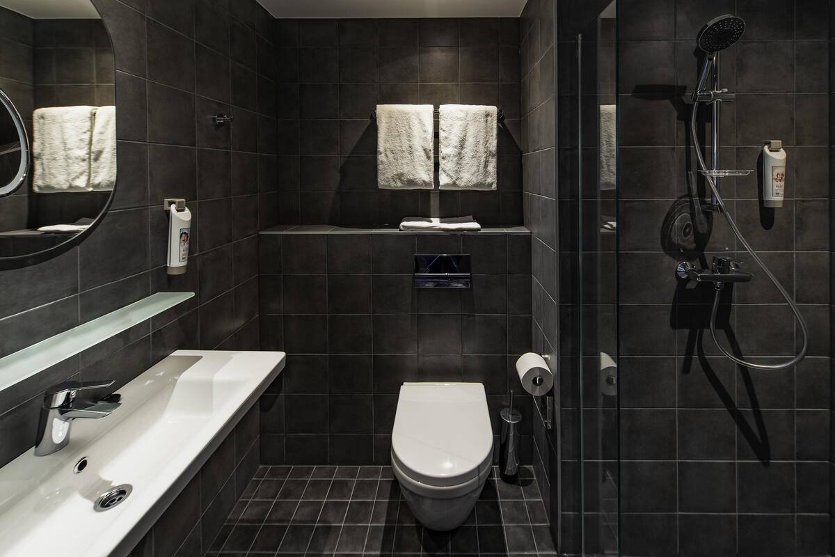 Une salle de bain moderne avec des toilettes blanches, une douche en verre et un grand miroir.
