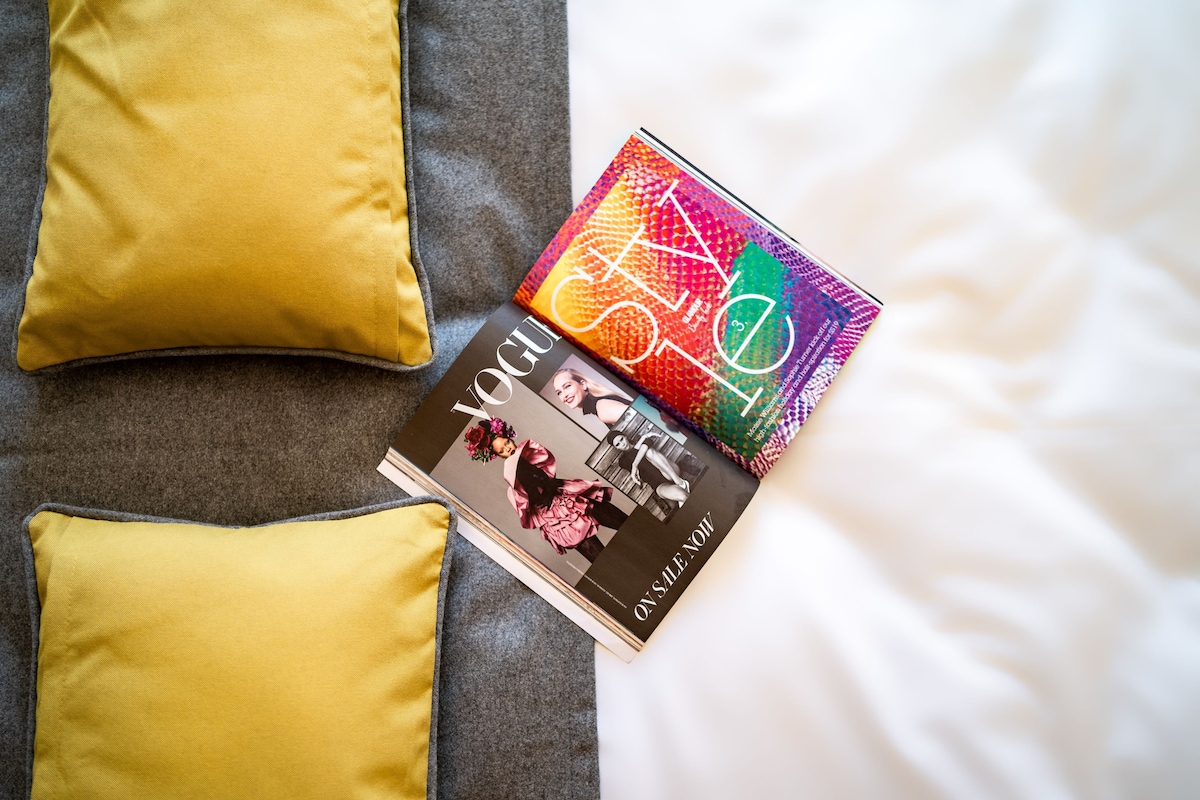 Un lit avec deux oreillers et un magazine dessus.
