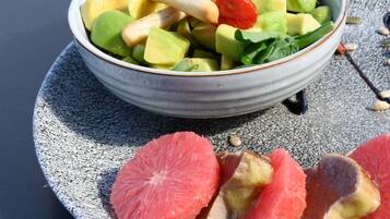 A bowl of fruit salad with grapefruit slices on a plate.