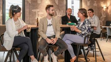 Een groep mensen zit aan een bar met krukken en voert een gesprek.