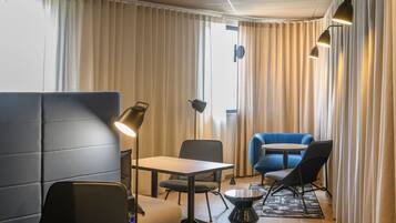 A modern hotel room with a seating area, a table, and a blue sofa.