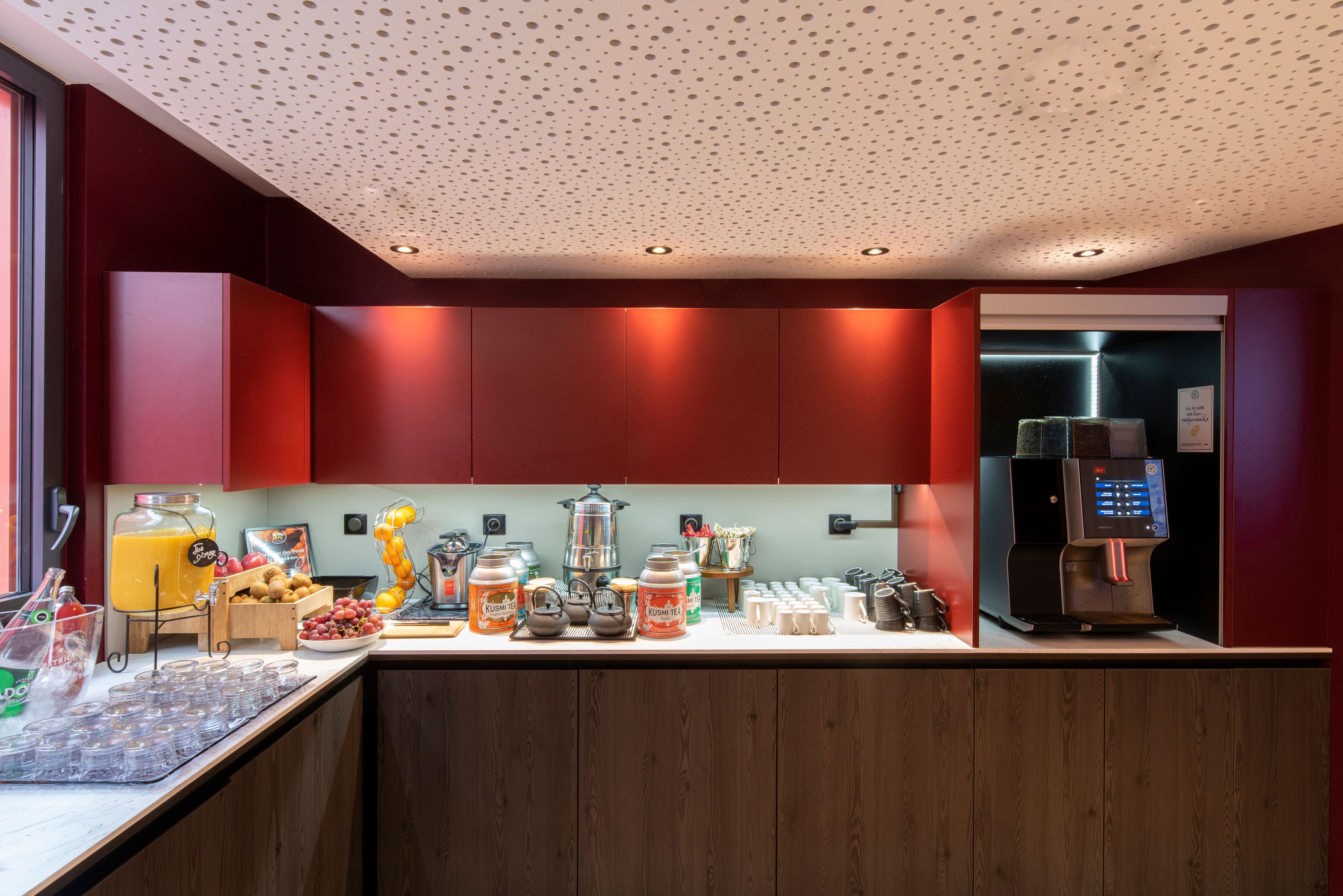 A modern kitchen with red cabinets, a coffee machine, and various breakfast items.