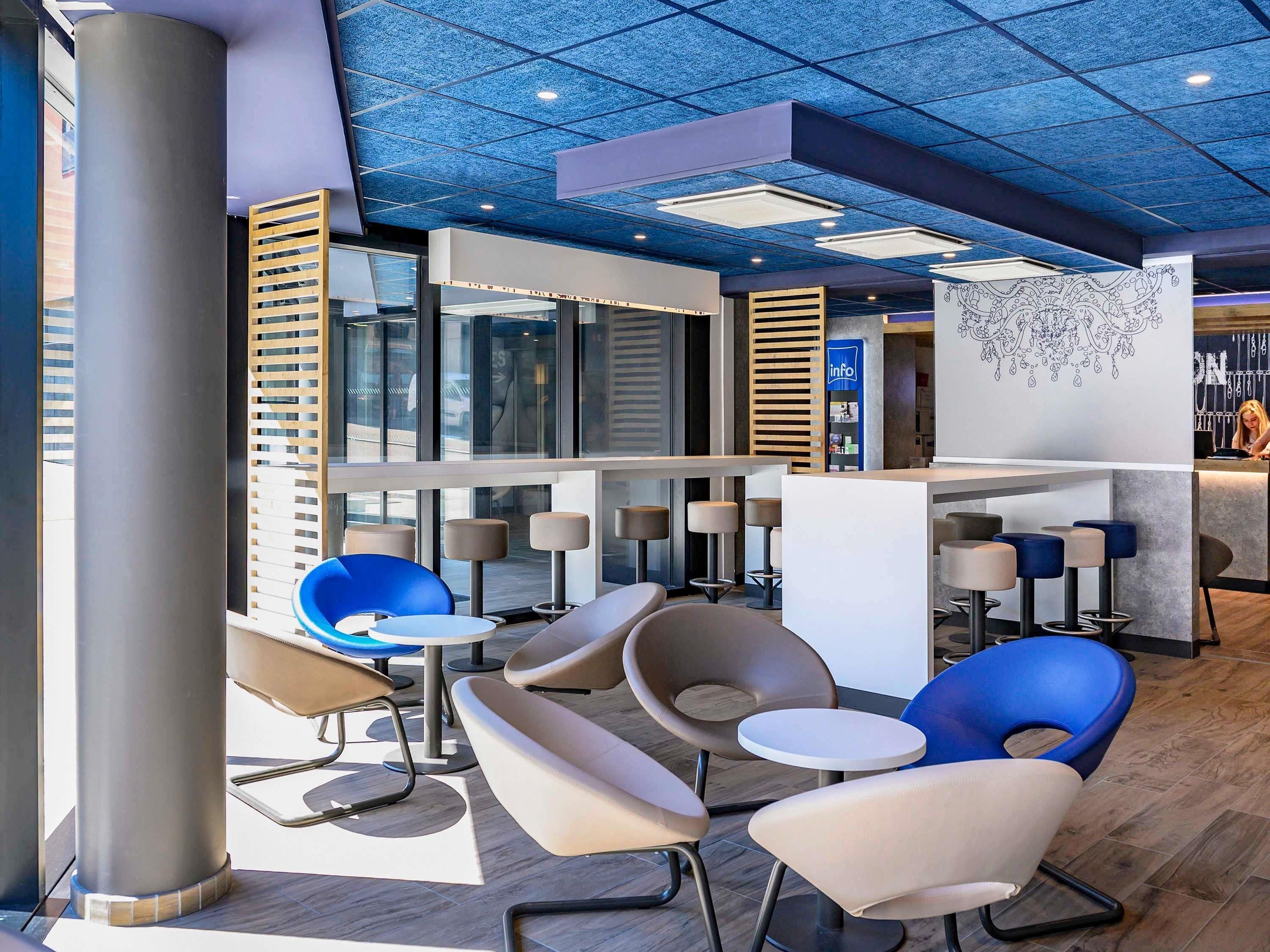 Een moderne lounge met zitplaatsen, een receptiebalie en een gestreept plafond.
