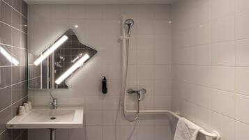 Une salle de bain équipée d’un lavabo, d’un miroir, d’une douche et d’un porte-serviettes.