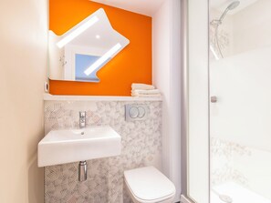 Un baño con lavamanos blanco, inodoro y ducha.