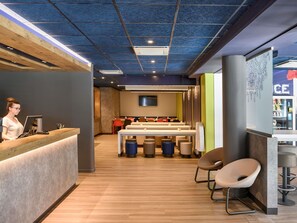 A modern interior with a reception desk, seating area, and a counter with a beverage display.