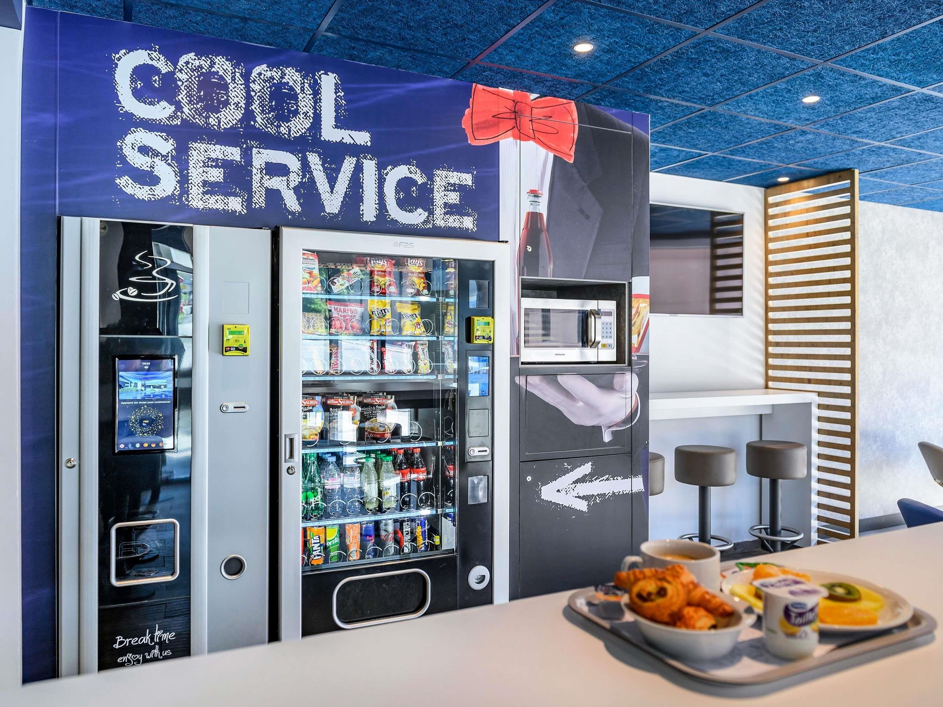 A vending machine area with a 'COOL SERVICE' sign, a microwave, and a tray of food.