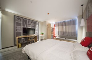 A modern hotel room with a large bed, a desk with a chair, a television, and a window with curtains. - Ibis Nantong Middle Renmin Rd Hotel (Nantong)