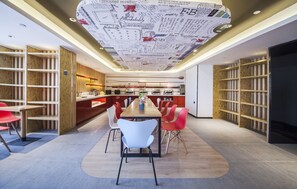 A modern dining area with a long table, red and white chairs, and a ceiling with a map design. - Ibis Nantong Middle Renmin Rd Hotel (Nantong)