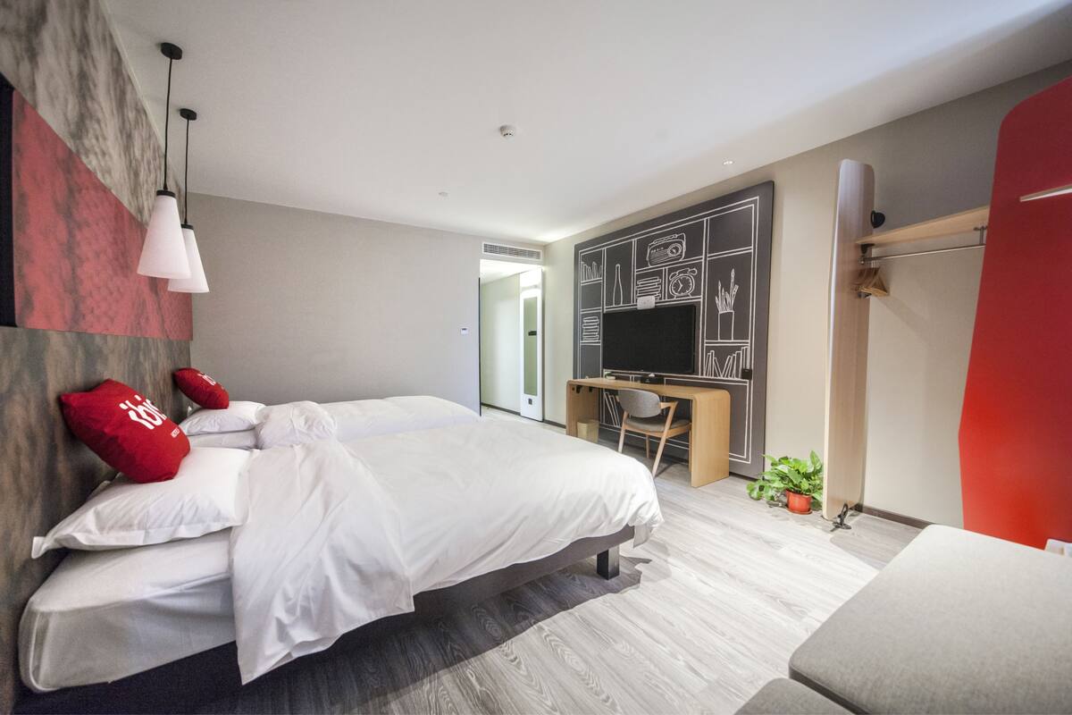 A modern bedroom with a bed, a desk, and a TV.