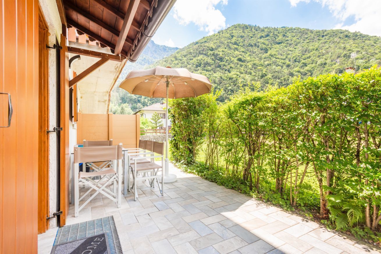 Eine Terrasse mit Tisch und Stühlen, eine Tür und Blick auf einen Berg.