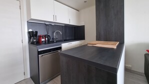A modern kitchen with a black countertop, stainless steel appliances, and white cabinetry. - Ski-in/out, Premium Comfort & 2 Bathrooms, Tignes Le Lac (Tignes)