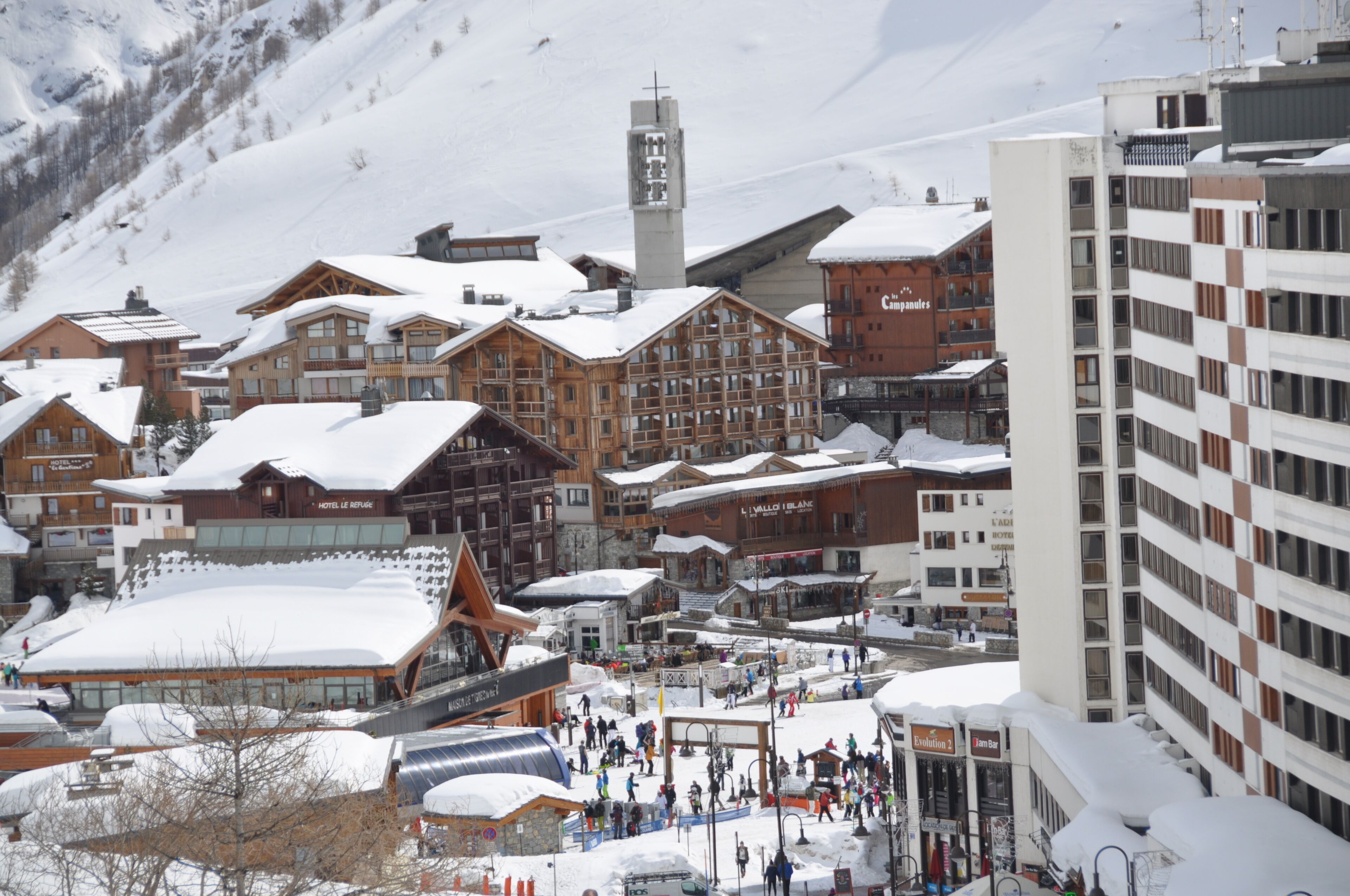 Une ville enneigée, avec des bâtiments en bois, dont un hôtel et une station de ski.