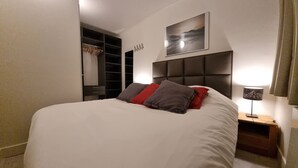 A neatly arranged bedroom with a large bed, a bedside table with a lamp, a wardrobe, and a painting on the wall. - Ski-in/out, Premium Comfort & 2 Bathrooms, Tignes Le Lac (Tignes)