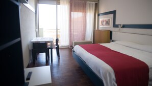 Una habitación de hotel con una cama, un escritorio y una silla.